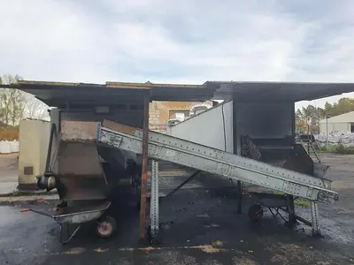 Briquetting machine for the production of charcoal briquettes including a hot air generator and conveyor