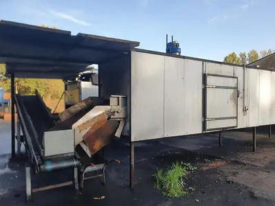 Briquetting machine for the production of charcoal briquettes including a hot air generator and conveyor