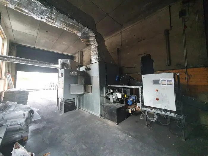 Briquetting machine for the production of charcoal briquettes including a hot air generator and conveyor