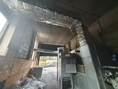 Briquetting machine for the production of charcoal briquettes including a hot air generator and conveyor