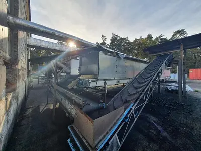 Briquetting machine for the production of charcoal briquettes including a hot air generator and conveyor