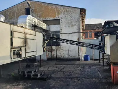 Briquetting machine for the production of charcoal briquettes including a hot air generator and conveyor