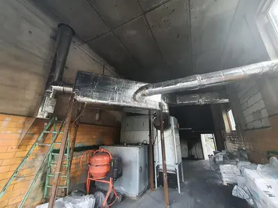 Briquetting machine for the production of charcoal briquettes including a hot air generator and conveyor
