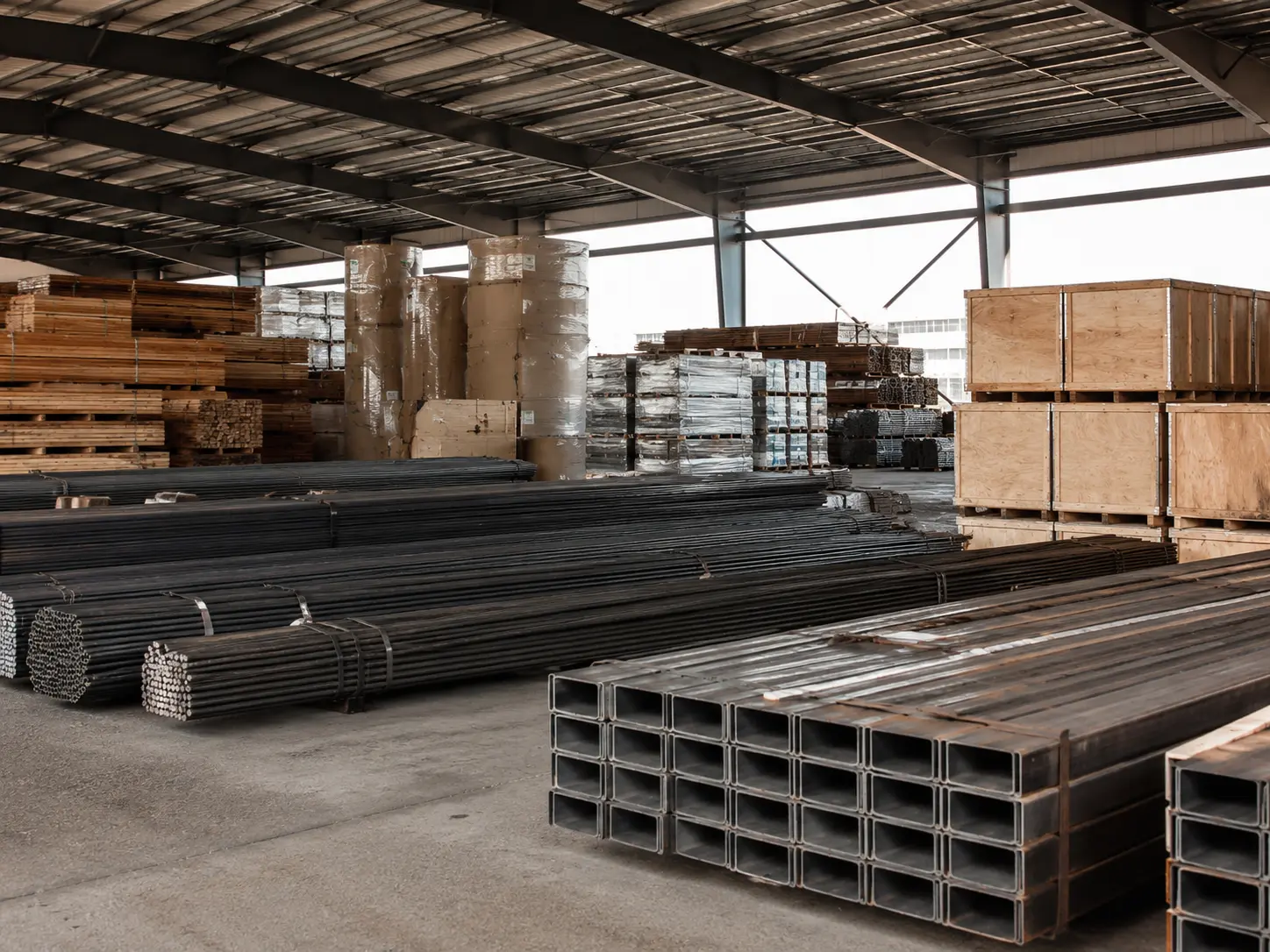Warehouse stocked with bundled steel, dimensional lumber, and wrapped material rolls