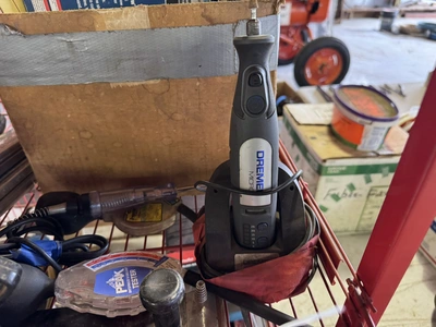 (1) small wire shelf with assorted contents, includes Dremel tool, small battery charger, pneumatic ...