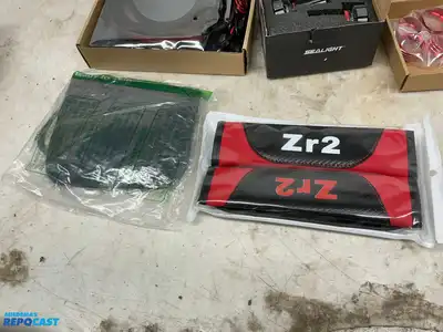 Box of various car parts and accessories including: red and black rearm rest covers, Chevy...