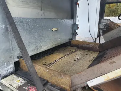Briquetting machine for the production of charcoal briquettes including a hot air generator and conveyor