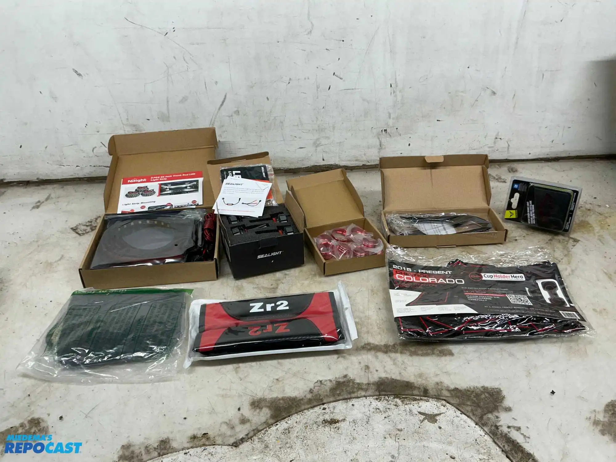 Box of various car parts and accessories including: red and black rearm rest covers, Chevy...