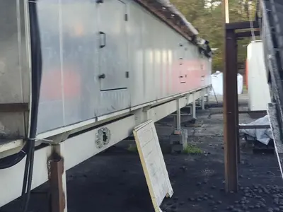 Briquetting machine for the production of charcoal briquettes including a hot air generator and conveyor